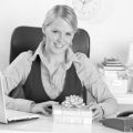 Happy business woman with present box at office desk