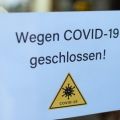 Biology and science. We're closed or postponed sticker.  Virus or bacteria cells. Global alert. Epidemic. Text in German: Closed due to COVID-19.